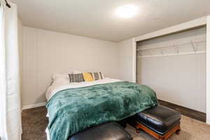 Carpeted bedroom with a textured ceiling and a closet