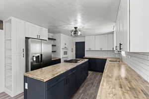 Kitchen featuring butcher block counters, open shelves, blue cabinetry, white cabinetry