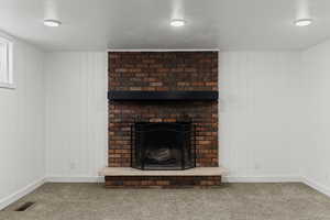 Detailed view of a fireplace, carpet flooring, and wood walls