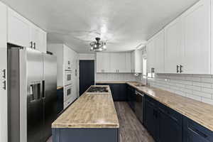 Kitchen with blue cabinetry, white cabinetry, appliances with stainless steel finishes