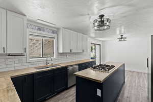 Kitchen with wooden counters, tasteful backsplash, a kitchen island, and light wood-style floors