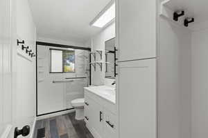 Full bath with vanity, wood tiled floors, and a shower stall