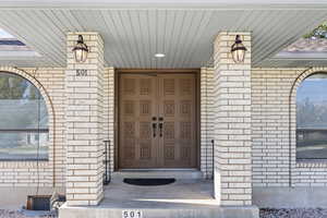 Property entrance with brick and a porch