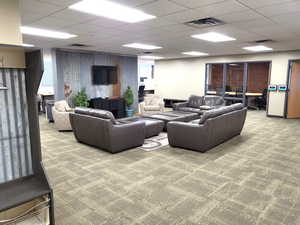 Carpeted living area with a drop ceiling and a desk