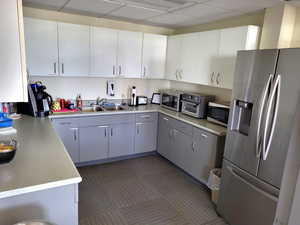 Kitchen with gray cabinetry, stainless steel appliances, a drop ceiling, light countertops, and white cabinetry