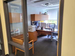 Office space with dark colored carpet and a paneled ceiling