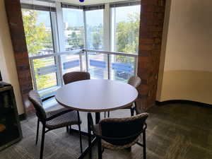 Dining space with healthy amount of natural light and dark colored carpet