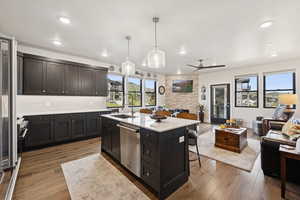 Kitchen with dark wood-style flooring, open floor plan, tasteful backsplash, decorative light fixtures, and a kitchen breakfast bar