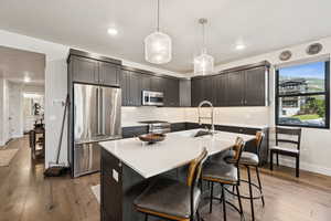 Kitchen featuring tasteful backsplash, high end appliances, dark wood-type flooring, a breakfast bar, and recessed lighting