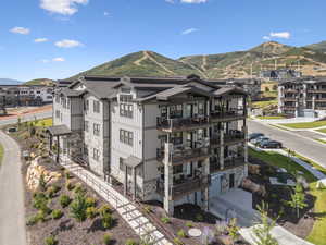 Rear view of house featuring stone siding, a balcony, and a mountain view