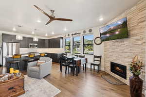 Living room with light wood finished floors, a ceiling fan, a tile fireplace, and recessed lighting
