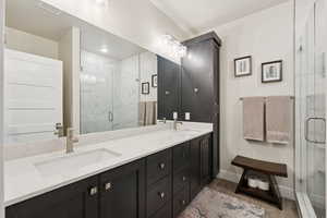Bathroom with double vanity, a marble finish shower, and dark wood-style floors