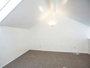 Additional living space with dark colored carpet and baseboards
