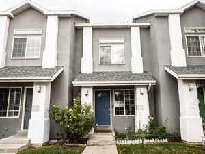 View of front facade featuring stucco siding and a shingled roof