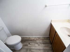 Half bath with dark wood-type flooring and vanity