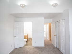 Unfurnished bedroom with light colored carpet, a closet, and connected bathroom