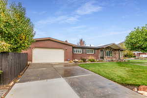 Single story home featuring driveway, brick siding, and an attached garage