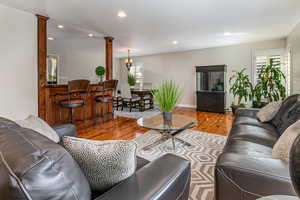 Living room featuring recessed lighting, wood finished floors, ornate columns, and a chandelier