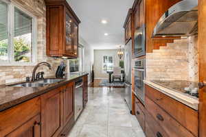 Kitchen featuring dark stone counters, backsplash, exhaust hood, Cherry cabinets, and recessed lighting