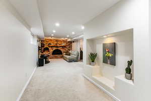 Interior space featuring a fireplace, light colored carpet, and recessed lighting