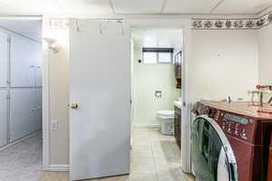Bathroom with washer / clothes dryer, light tile patterned floors, and a paneled ceiling