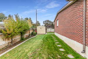 Fenced backyard featuring a shed