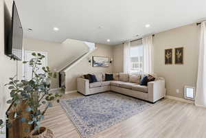 Living area with light wood-type flooring, recessed lighting, and stairs