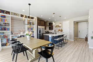 Dining space featuring light wood-style floors, recessed lighting, and a chandelier