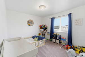 Bedroom with light carpet and a crib