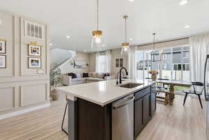 Kitchen featuring pendant lighting, stainless steel dishwasher, an island with sink, light wood finished floors, and recessed lighting