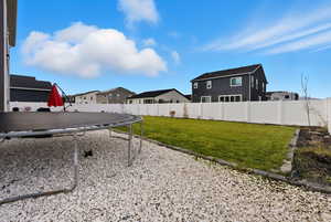 Fenced backyard featuring a trampoline and a residential view