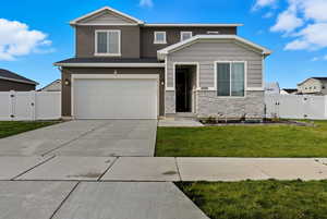 View of front of property featuring a gate, stone siding, concrete driveway, and a garage