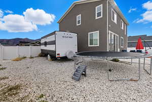 Rear view of house featuring a trampoline, a mountain view, and stucco siding