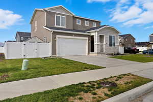 View of front of house with stucco siding, concrete driveway, a gate, stone siding, and a garage