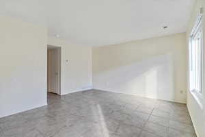 Empty room featuring plenty of natural light and light tile patterned floors