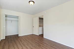 Unfurnished bedroom with a closet, dark wood-type flooring, and washer / clothes dryer