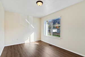 Empty room with baseboards and dark wood-style flooring