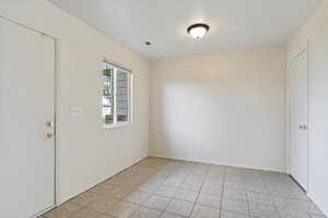Unfurnished room featuring light tile patterned floors and baseboards