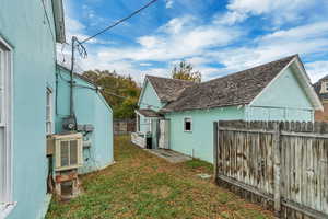 View of side of property featuring a fenced backyard, stucco siding, and an outdoor structure