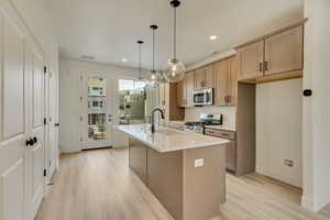 Kitchen featuring stainless steel appliances, light wood-style flooring, a kitchen island with sink, decorative light fixtures, and recessed lighting