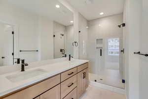Bathroom featuring double vanity, a shower stall, and recessed lighting