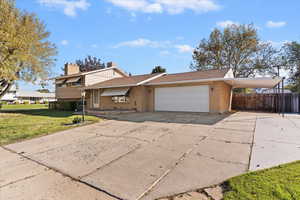 Split level home with concrete driveway, brick siding, a chimney, and an attached garage