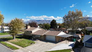 View of front facade with a mountain view, driveway, roof with shingles, a front yard, and a residential view