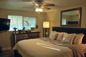 Bedroom with ceiling fan, dark wood-type flooring, and a textured ceiling