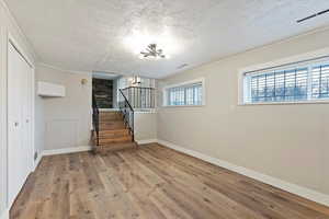 Unfurnished living room with a textured ceiling, wood finished floors, and stairway