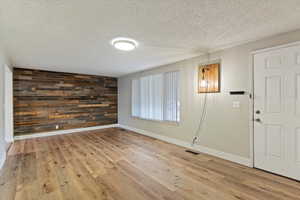 Foyer entrance featuring wooden walls, a textured ceiling, light wood-style floors, and an accent wall