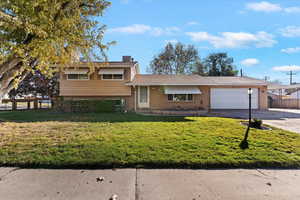 Tri-level home with brick siding, a chimney, concrete driveway, and an attached garage