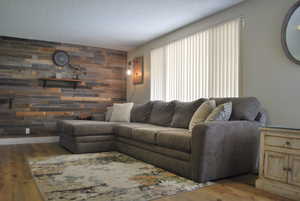 Living area featuring a textured ceiling, wooden walls, and wood finished floors