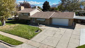 View of front of house with a front yard, driveway, roof with shingles, and a garage