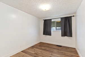 Empty room with a textured ceiling and wood finished floors
